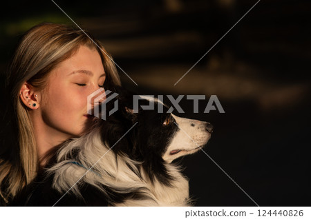 Young Caucasian woman hugging her border collie dog while walking in the park.  124440826