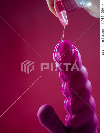 Lube pouring on pink dildo on pink background. Lube pouring on pink dildo on pink background. 124440860