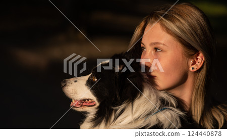 Young Caucasian woman hugging her border collie dog while walking in the park. Young Caucasian woman hugging her border collie dog while walking in the park. 124440878