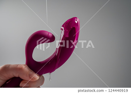 Lube pouring on pink dildo on white background.  124440919