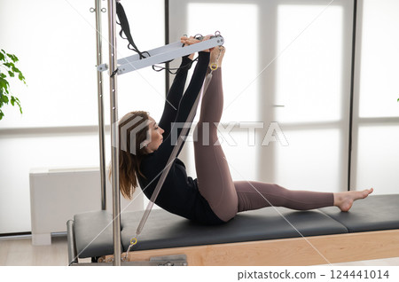 Woman doing Pilates on reformer. 124441014
