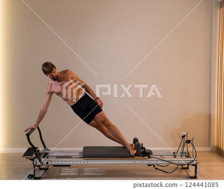 A man doing Pilates on a reformer. A man doing Pilates on a reformer. 124441085