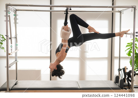 Asian woman doing aerial exercise on reformer machine.  124441098