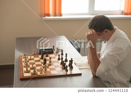 Caucasian man thinking about a chess move. Caucasian man thinking about a chess move. 124441118
