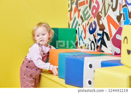 curly-haired girl is playing with big cubes. curly-haired girl is playing with big cubes. 124441219
