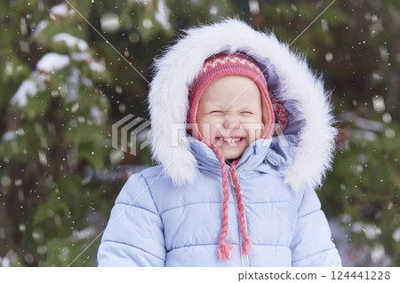 Happy toddler is standing under a winter snowy spruce. Happy toddler is standing under a winter snowy spruce. 124441228