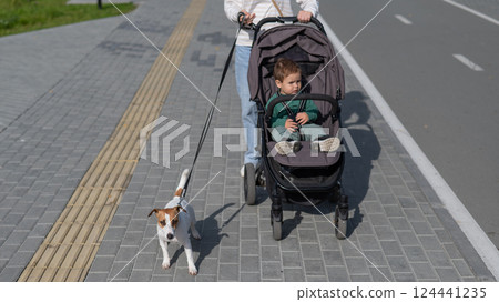 Caucasian woman walks in the park with her one-year-old son and Jack Russell Terrier dog.  124441235