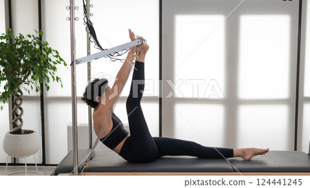 Asian woman doing pilates on reformer.  124441245