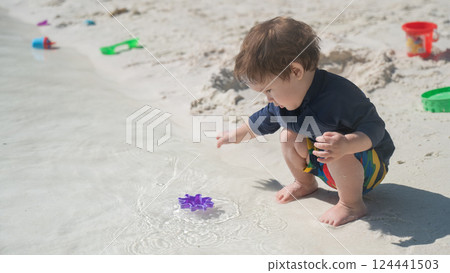 One year old Caucasian boy plays in the sand on the seashore. One year old Caucasian boy plays in the sand on the seashore. 124441503