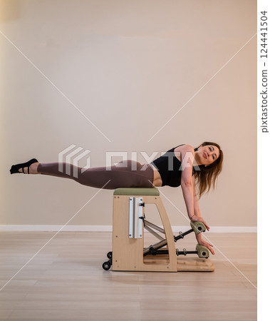 Asian woman doing pilates classic chair. Asian woman doing pilates classic chair. 124441504