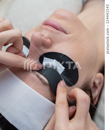 The master applies protective patches that do not let in ultraviolet rays before LED eyelash extensions. The master applies protective patches that do not let in ultraviolet rays before LED eyelash extensions. 124441543