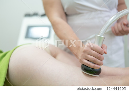 Caucasian woman on hardware anti-cellulite massage. Thigh cavitation procedure. 124441605