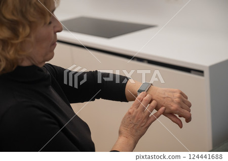 Elderly Caucasian woman looking at smart watch. Close-up of hands.  124441688