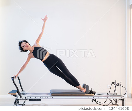 Asian woman doing pilates on reformer.  124441698