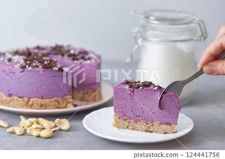 Vegan raw blueberry cake. The presence of a person without a face. The hand with the spoon breaks off a piece of cake 124441756