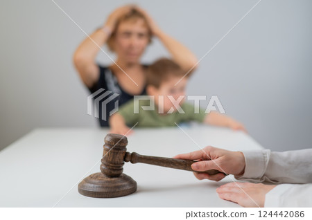 A judge hits a gavel against the backdrop of an elderly woman holding a child.  124442086