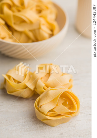 Italian pasta tagliatelle. Uncooked noodle pasta on kitchen table. Italian pasta tagliatelle. Uncooked noodle pasta on kitchen table. 124442397