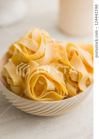 Italian pasta tagliatelle. Uncooked noodle pasta in bowl on kitchen table. 124442398