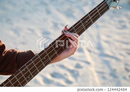 Girl Plays Bass Music Instrument On The Beach At Sunset Near Ocean 124442484