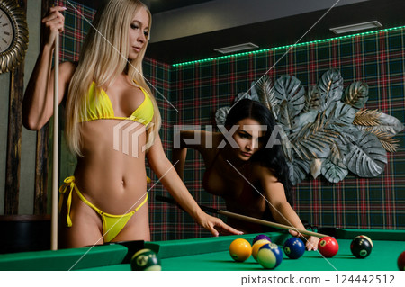 Women posing in lingerie while playing billiards in a stylish indoor setting 124442512