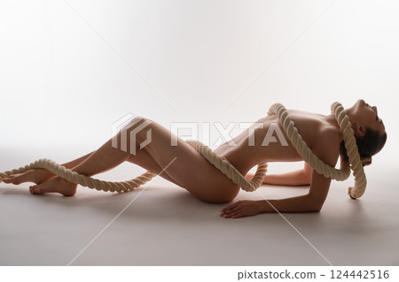 Woman posing gracefully with rope in a studio setting for a sport-themed shoot 124442516