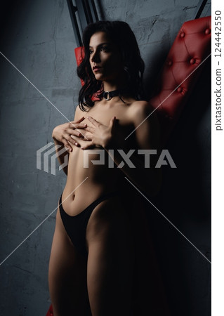 Woman Posing in Studio With Red Upholstery prepared for sexual bdsm game 124442550