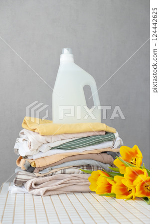 mock up, conditioner, or laundry gel against stack of clean clothes on a table with tulip flowers. 124442625