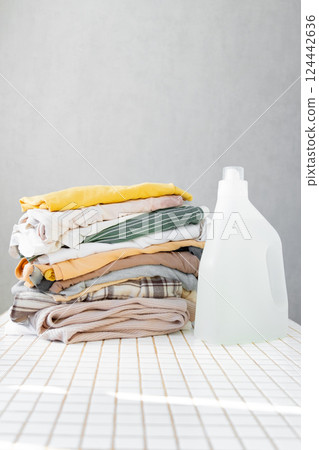mock up, conditioner, or laundry gel against stack of clean clothes on a table with tulip flowers. mock up, conditioner, or laundry gel against stack of clean clothes on a table with tulip flowers. 124442636