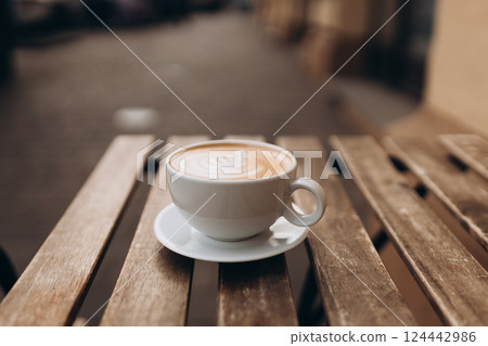 Cup of coffee on the wooden table with latte art. Street coffee, top view. Coffee in a white cup with latte art. 124442986