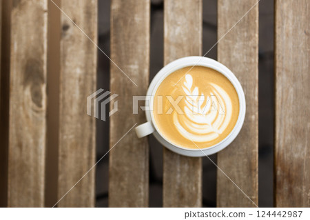 Cup of coffee on the wooden table with latte art. Street coffee, top view. Coffee in a white cup with latte art. 124442987