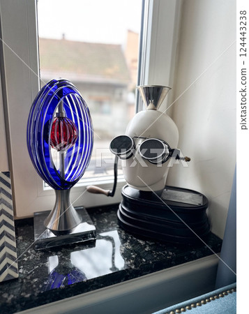 Futuristic sculpture and quirky figure on a windowsill in bright daylight. Creativity, imagination, and the blend of science with artistic expression Futuristic sculpture and quirky figure on a windowsill in bright daylight. Creativity, imagination, and the blend of science with artistic expression 124443238