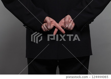 Businessman in black suit crosses his fingers behind his back. Concept of corporate espionage 124444065