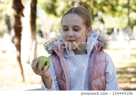 Happy young girl with apple fruit in park. Child 10 years old 124444106