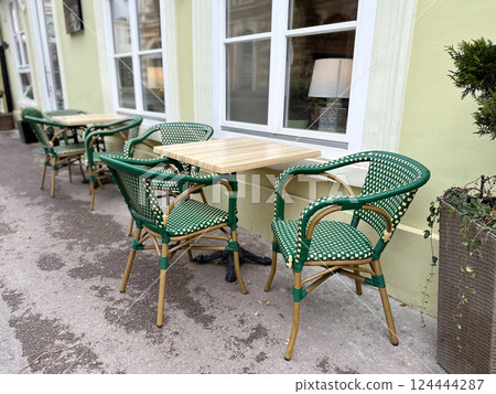 Outdoor cafe seating with empty tables on a quiet city street. Urban lifestyle, social routine, and relaxed street culture. Outdoor cafe seating with empty tables on a quiet city street. Urban lifestyle, social routine, and relaxed street culture. 124444287