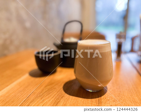 Hot beverage on a wooden table in a cozy cafe interior. Comfort, morning ritual, and peaceful lifestyle through simple objects 124444326