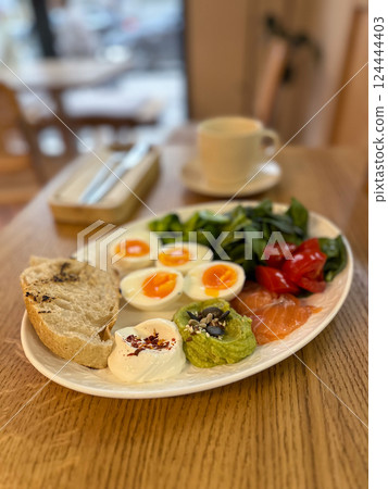 Balanced breakfast with eggs, salmon and vegetables on wooden table. Healthy eating, mindful routine and morning energy boost 124444403