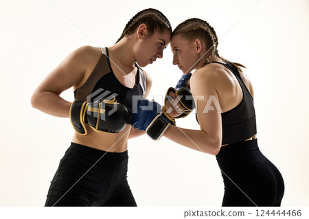 Two focused female fighters in boxing gloves facing off in fighting stance with intensity and determination. Two focused female fighters in boxing gloves facing off in fighting stance with intensity and determination. 124444466