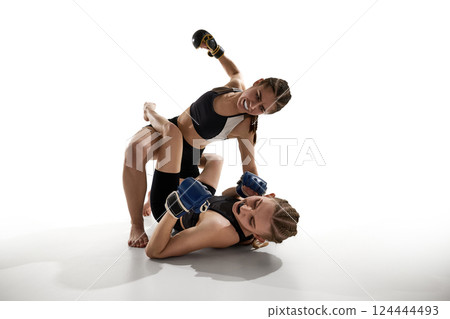 Two female MMA fighters in emotional ground-and-pound moment, showing fierce expression and intensity. 124444493