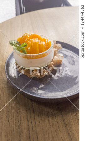 Panna cotta dessert topped with peach jam in a clear bowl. 124444562
