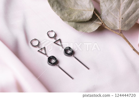 Female Jewelry. Vintage bijouterie jewelry. Beautiful handmade silver earrings on pink silk background. Flat lay, top view copy space and empty space for text Female Jewelry. Vintage bijouterie jewelry. Beautiful handmade silver earrings on pink silk background. Flat lay, top view copy space and empty space for text 124444720