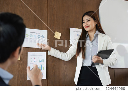 Engagement and Professionalism. A confident businesswoman presents key project metrics while engaging with her audience. 124444968