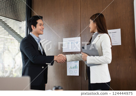 Handshake and Agreement. Two business professionals sealing a deal with a firm handshake in a modern office. 124444975