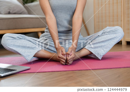 Yoga and Flexibility. A woman practicing yoga with a focus on stretching in a calm home environment. 124444979