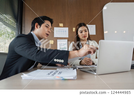 Data Presentation and Collaborative Problem-Solving. A professional duo analyzes charts and graphs on a laptop during a strategic meeting. Data Presentation and Collaborative Problem-Solving. A professional duo analyzes charts and graphs on a laptop during a strategic meeting. 124444985
