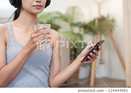 Self-Care and Digital Connection. A woman listens to music while enjoying a refreshing drink. Self-Care and Digital Connection. A woman listens to music while enjoying a refreshing drink. 124444991