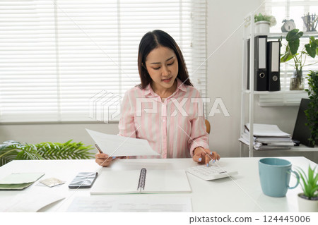 Home Office and Analytical Review. A person assessing documents while noting important information in a modern workspace. 124445006