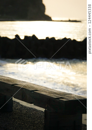 An image of someone sitting alone on a beach bench at dusk, lost in thought 124445338