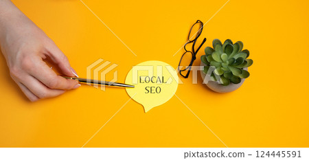 Local SEO, Search Engine Optimization. Process of optimizing a website or online presence to improve its visibility in local search results. A woman's hand points to notes 124445591