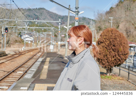 A woman waiting for a train on the station platform in the countryside 124445836