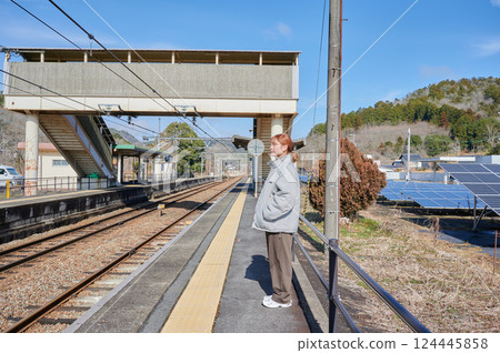 A woman waiting for a train on the station platform in the countryside 124445858